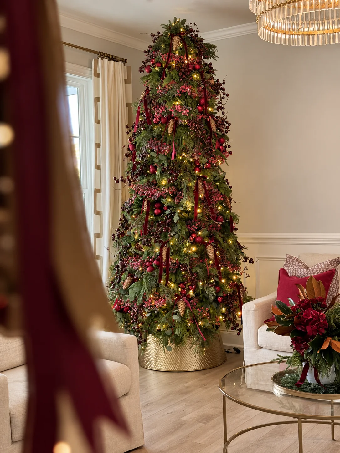 Christmas tree decorated with burgundy ribbon, red berries, and warm lights in an elegant living room